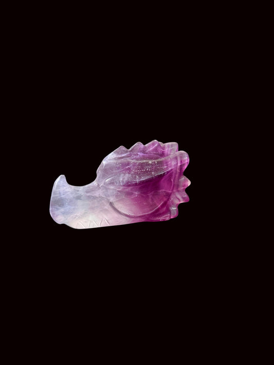 Lavender purple fluorite crystal dragon head carving side view on dark table with altar background
