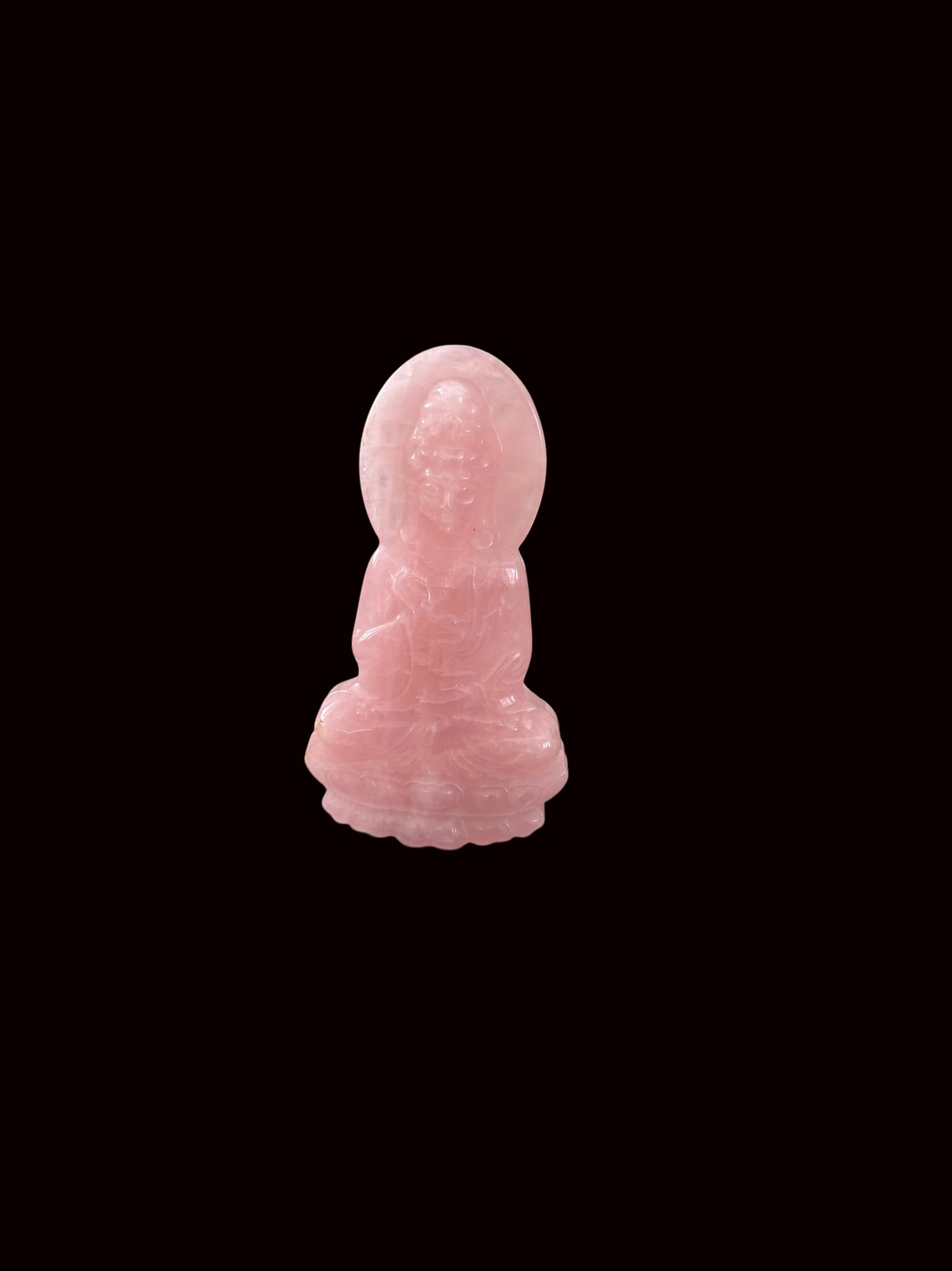 Rose quartz Guan Yin carving lifestyle shot on dark table with altar background