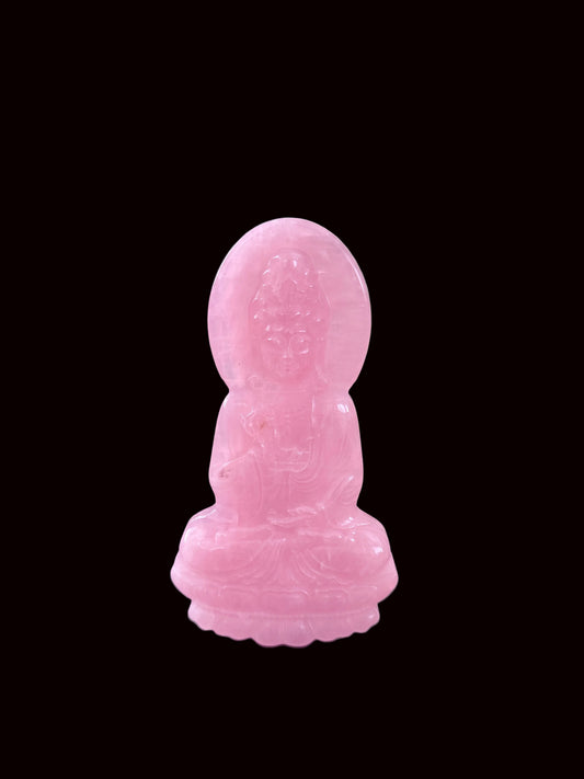 Rose quartz Guan Yin carving lifestyle shot on dark table with Buddha altar in background