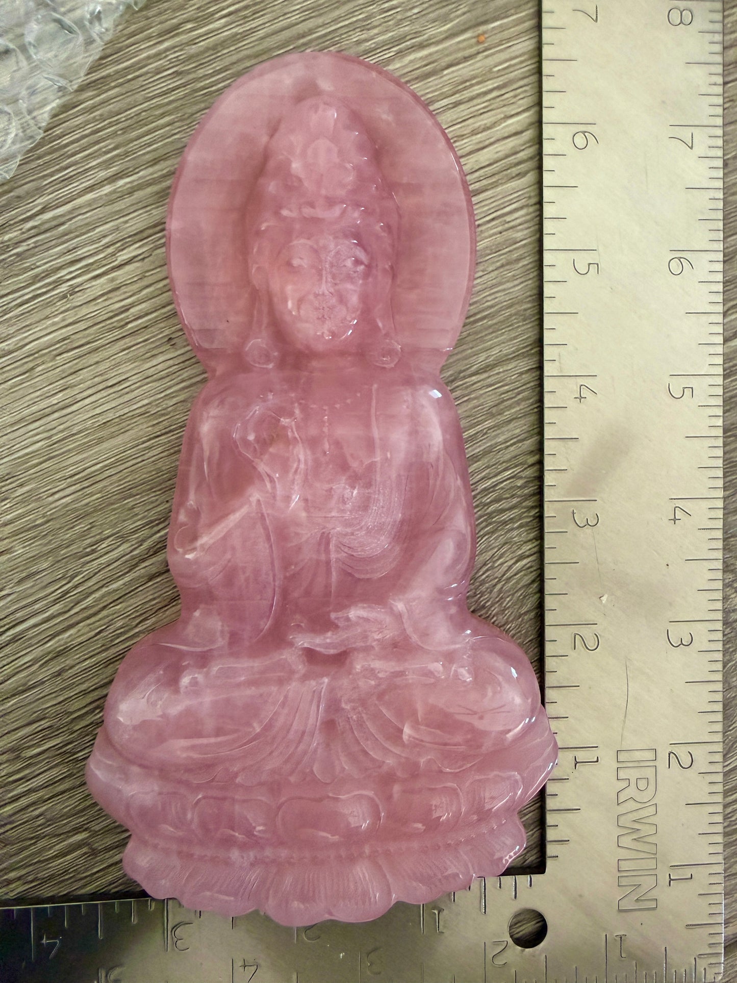 Rose quartz Guan Yin carving close-up showing intricate lotus throne and robe detail