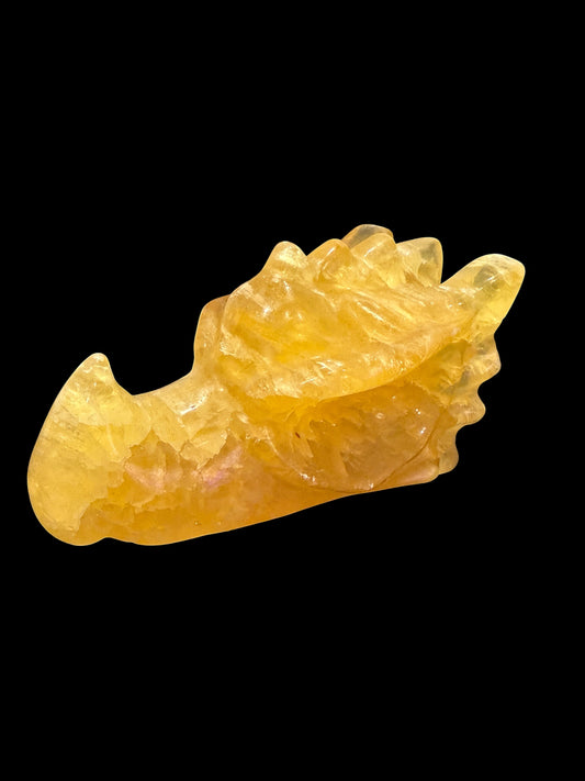Yellow fluorite crystal dragon head carving front view on black background