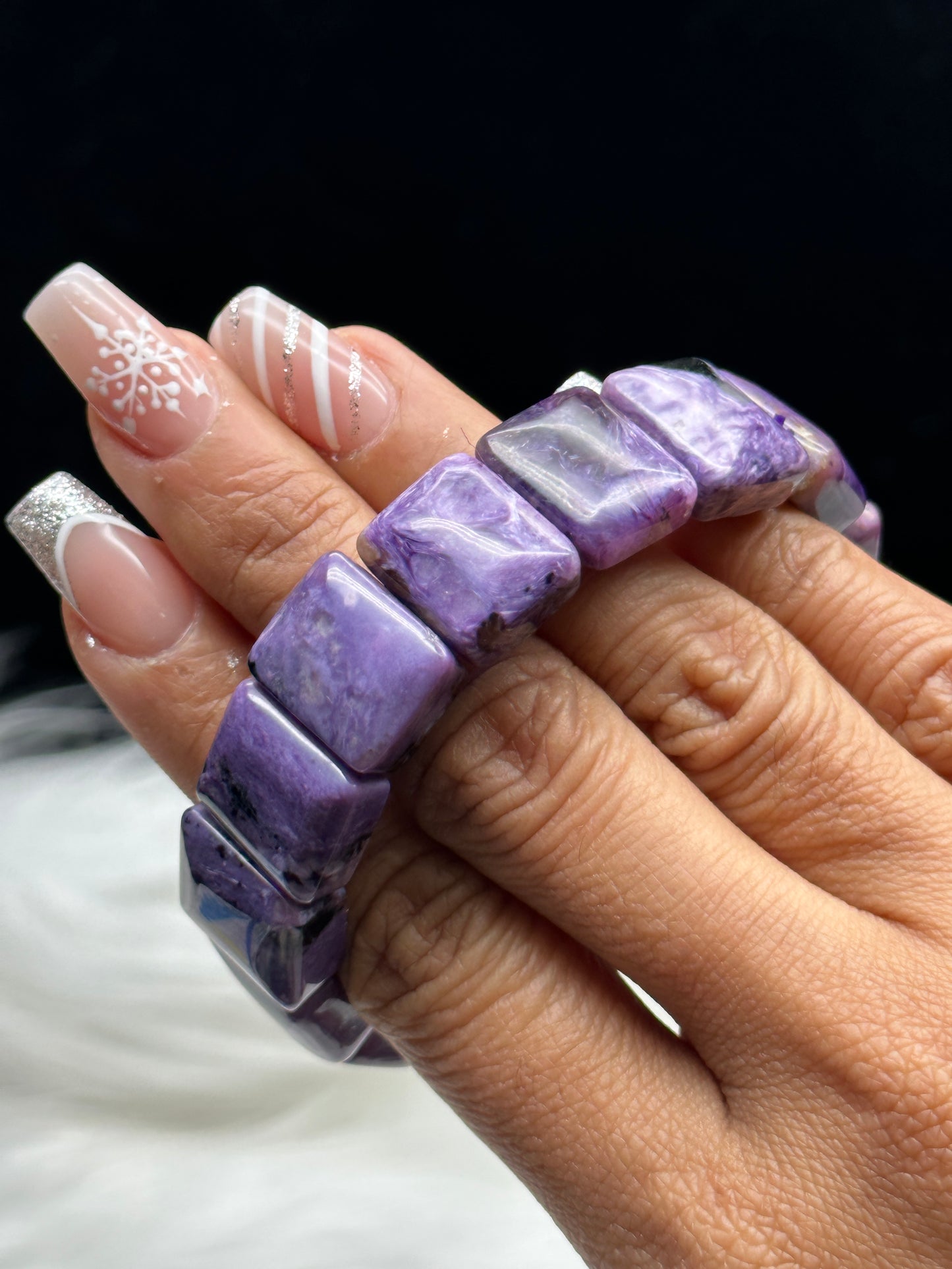 Natural charoite crystal bangle bracelet - held in hand showing deep violet color