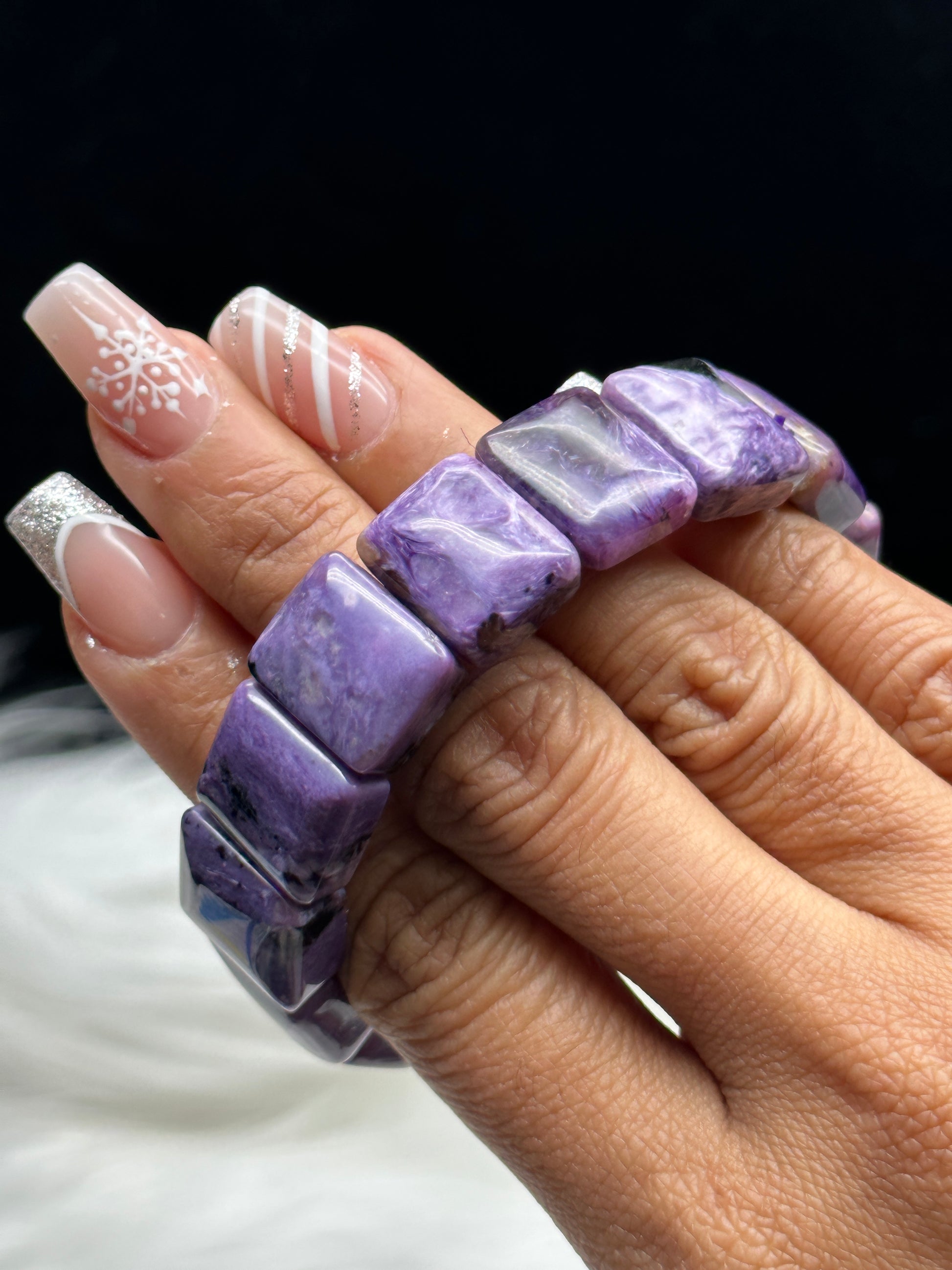 Natural charoite crystal bangle bracelet - held in hand showing deep violet color
