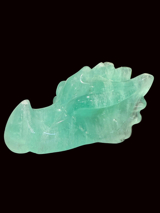 Green fluorite crystal dragon head carving side view on dark table