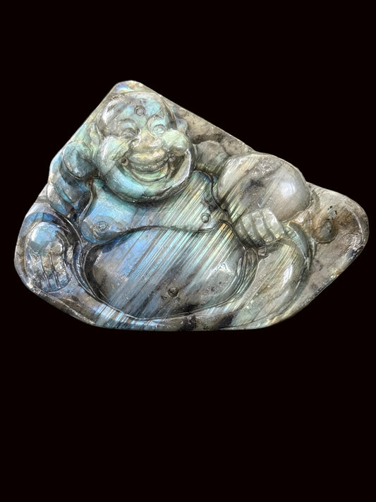 Labradorite laughing Buddha carving standing on dark table showing blue-green flash and front detail