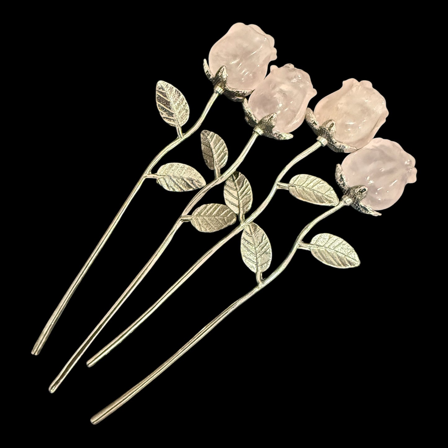 Three natural rose quartz crystal roses on silver stems - flat lay view
