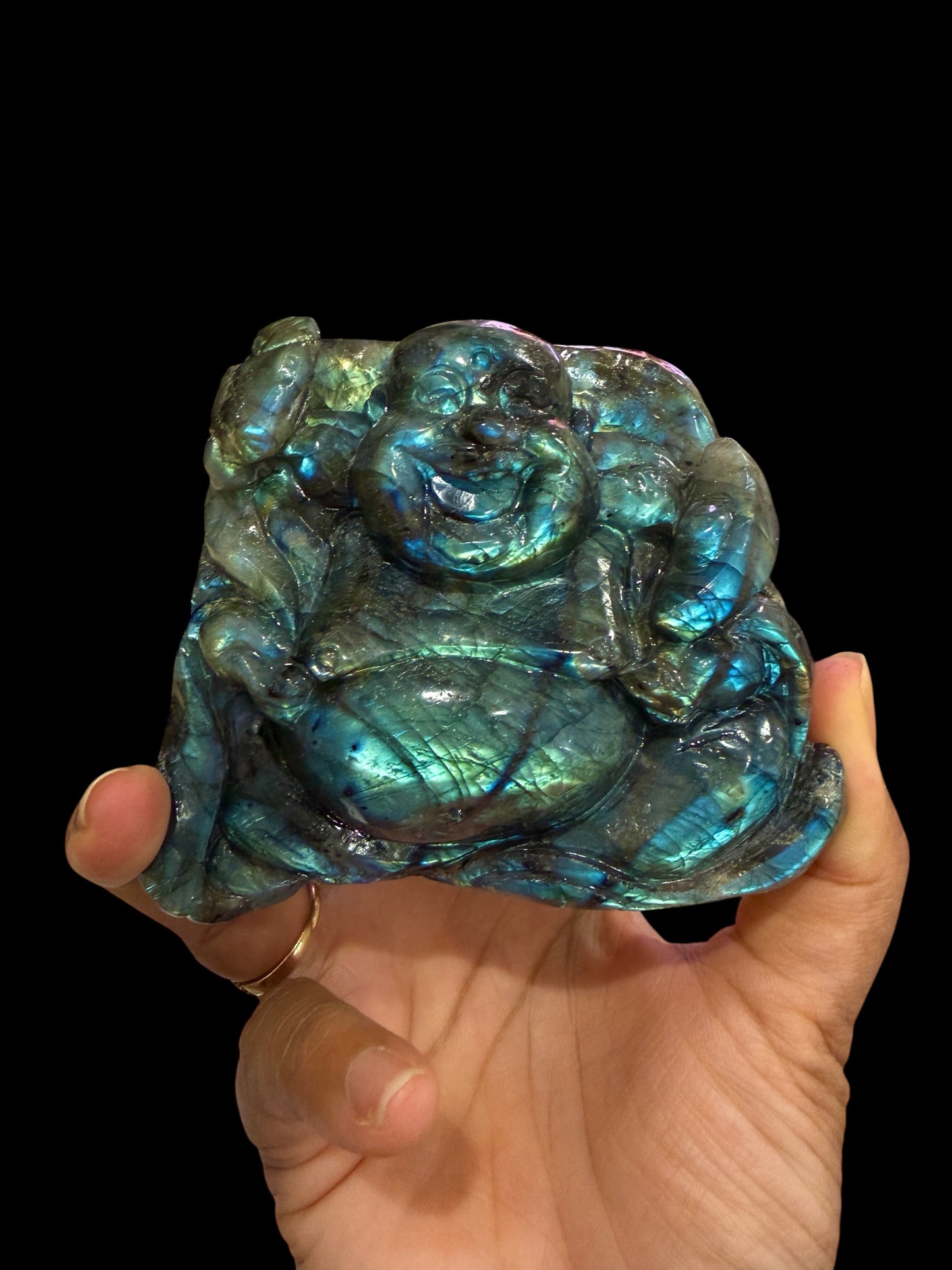 Hand-carved labradorite Buddha carving held in hand to show scale, 3 inches tall