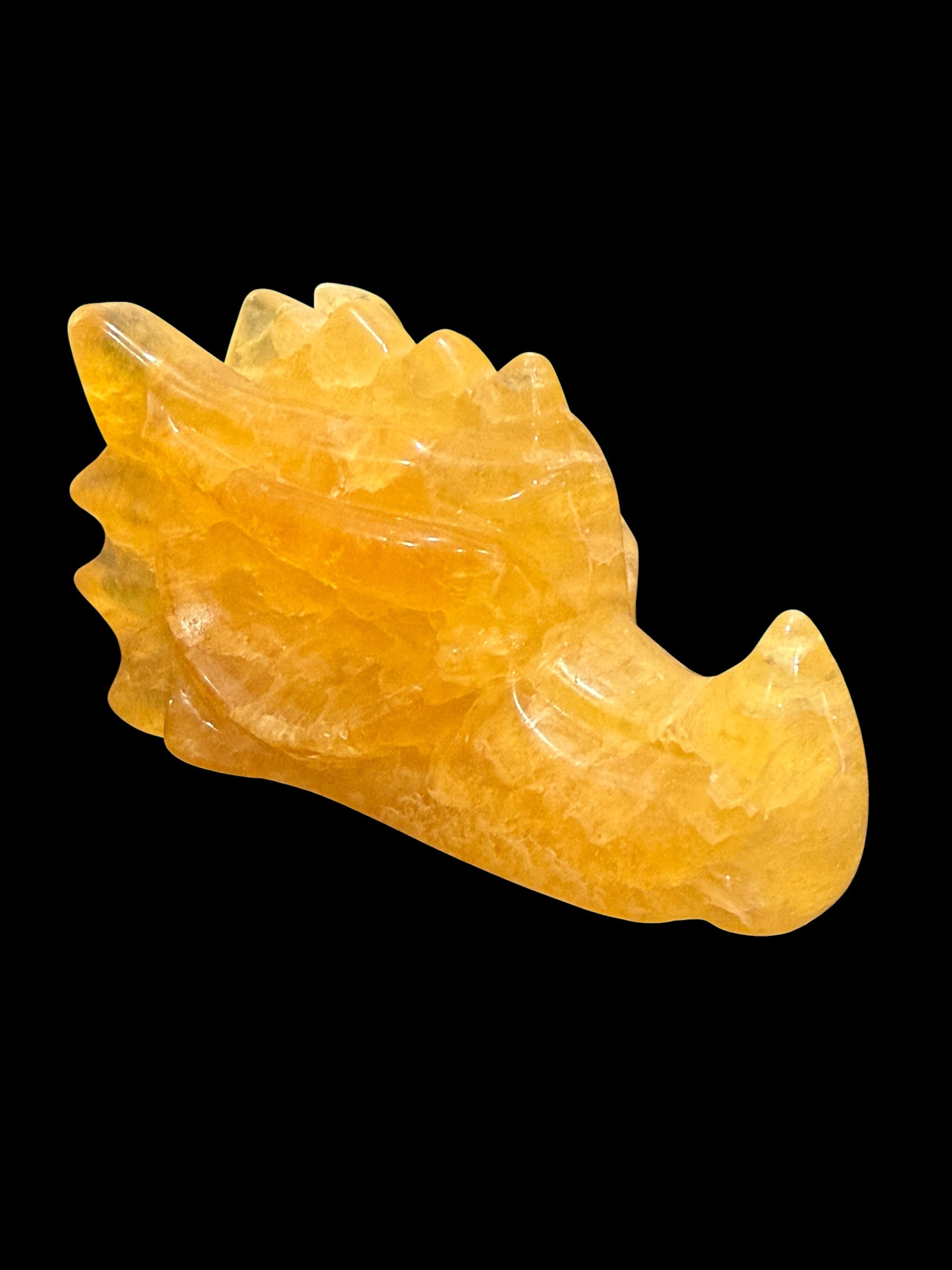 Yellow fluorite crystal dragon head carving side view on black background